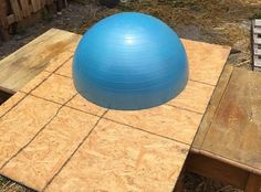 a blue ball sitting on top of a wooden table in the middle of a yard