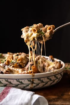 a close up of a spoonful of pasta with mushrooms and parmesan cheese