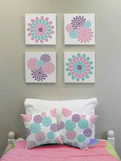 three flower paintings on the wall above a bed with pink and blue sheets, pillows and blankets