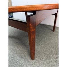 a close up of a wooden table on carpeted floor with white walls in the background