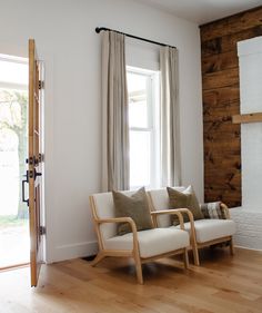 a living room filled with furniture and a fire place in front of a window on top of a hard wood floor