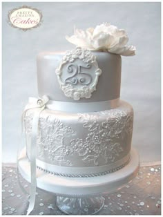 a three tiered wedding cake with white flowers on the top and silver trimmings