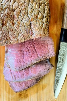 some meat is on a cutting board next to a knife