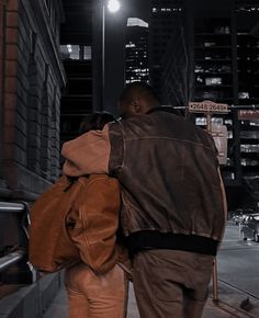 two people walking down the street at night with their backs to each other and one person carrying a backpack