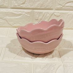 two pink bowls sitting on top of a white tile floor next to each other,