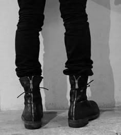 a pair of black boots with zippers on the bottom and side, standing in front of a white wall