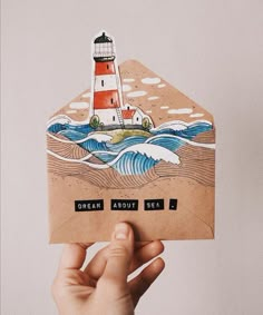 a hand holding up a card with a lighthouse on it