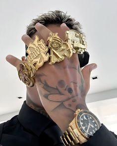 a man with tattoos holding his hands up to his face while wearing several different watches