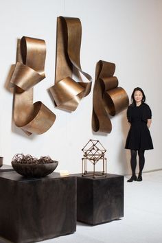 a woman standing in front of some art pieces