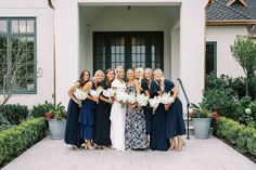 a group of women standing next to each other in front of a building with flowers