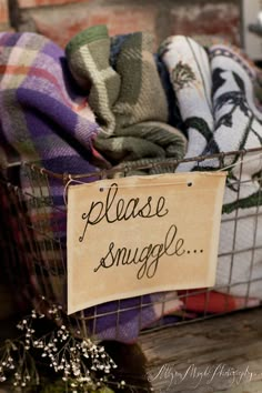 a basket filled with lots of blankets next to a sign that says please snuggle