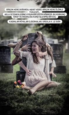 a woman sitting on the ground next to a grave