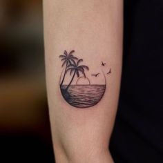 a small tattoo on the arm of a woman with palm trees and birds flying around