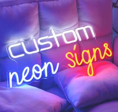 a neon sign that says custom neon signs on the back of a couch with pillows