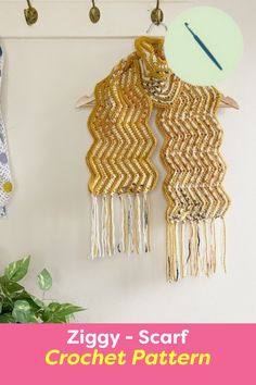 two scarves hanging on a wall next to a potted plant and clock with the words ziggy - scarf crochet pattern