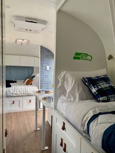 the interior of an airstream with bunk beds and white cupboards on each side