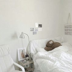 a teddy bear sitting on top of a bed next to a white chair and lamp