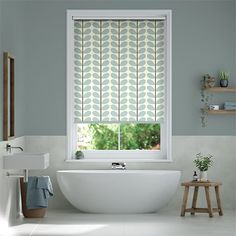 a white bath tub sitting under a window next to a sink in a room with blue walls