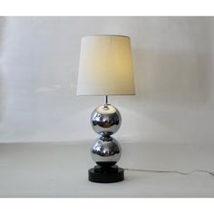 a chrome ball lamp on a black base with a white linen shade in the corner