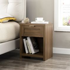 a nightstand with books on it next to a white bed in a gray and yellow bedroom