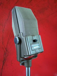 an old fashioned microphone on a stand against a red wall