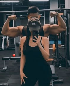 a woman is taking a selfie with her cell phone in front of a gym machine