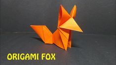 an origami fox made out of orange paper on a black surface with the words origami fox written below it