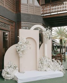 an outdoor ceremony setup with white flowers and greenery in front of a large building