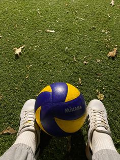 a person's feet are shown with a blue and yellow ball in front of them