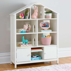 a white doll house shelf with books and toys