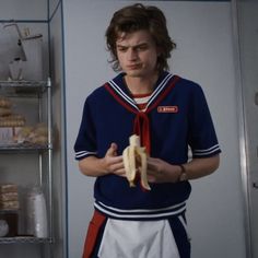 a young man holding a banana in his hand and wearing a sailor's outfit