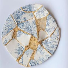 a blue and white plate with gold trimmings sits on a white table top