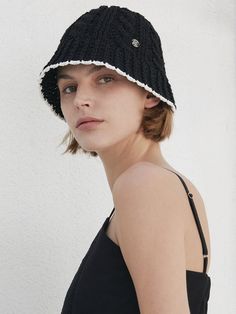 a young woman wearing a black hat with white trims on the brim and sides