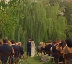 a bride and groom standing at the end of their wedding ceremony in front of a willow tree