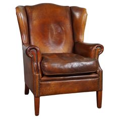 a brown leather chair with nailing on the armrests and back rests against a white background