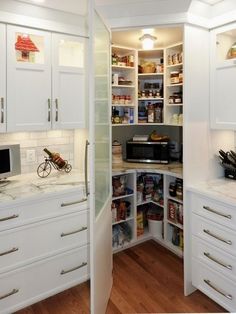 an open pantry with white cabinets and drawers