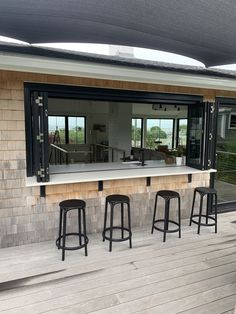 three stools are sitting on the deck near an open patio area with sliding glass doors