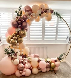 an arch made out of balloons and greenery is displayed in the corner of a room