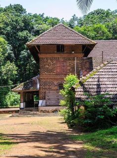 an old brick building surrounded by lush green trees