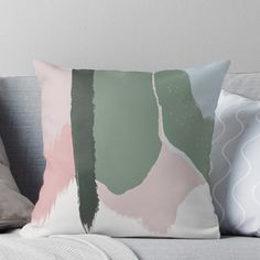 a couch with two pillows on it and one pillow is green, pink and white