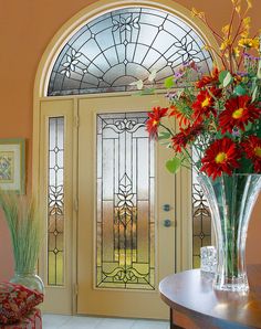 a vase filled with flowers sitting on top of a table next to a glass door