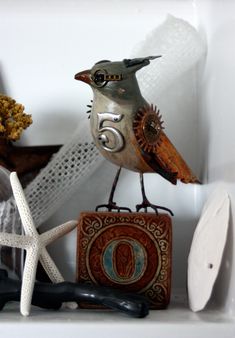 a small bird sitting on top of a shelf next to other objects and decor items