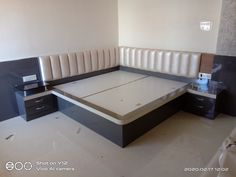 an empty bed frame in a room with white and black furniture on the floor next to two nightstands