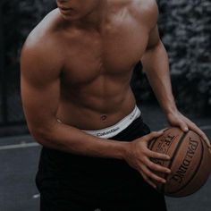 a shirtless man holding a basketball in his hand and looking at the camera while standing on a court