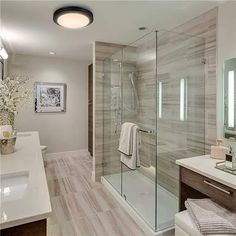 a bathroom with a walk in shower next to a white sink and counter top under a mirror