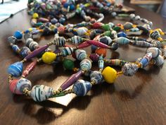 a wooden table topped with lots of colorful beaded necklaces on top of it