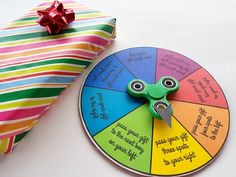 a colorful wheel of fortune next to a present bag with a red bow on it