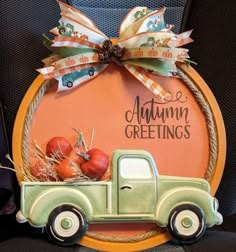 an orange and green truck with pumpkins in the back seat is adorned with a bow