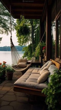 a hammock hanging from the side of a house next to a body of water