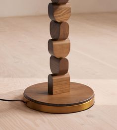 a lamp made out of wooden blocks sitting on top of a hard wood floor next to a white wall